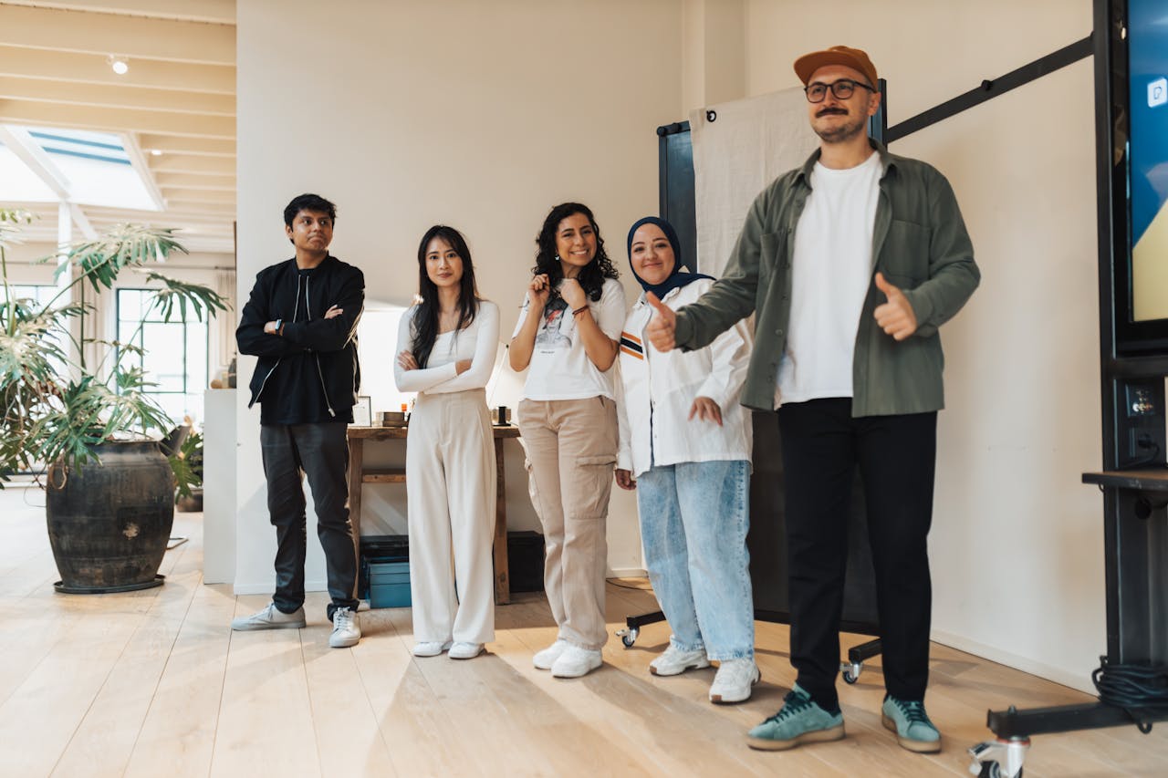 A group of five diverse professionals standing together, smiling indoors.